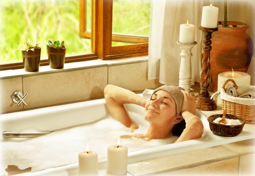 Woman taking bath, happy female relaxing at spa resort, young healthy girl at vacation, lady lying down in hot water, travel to luxury spa