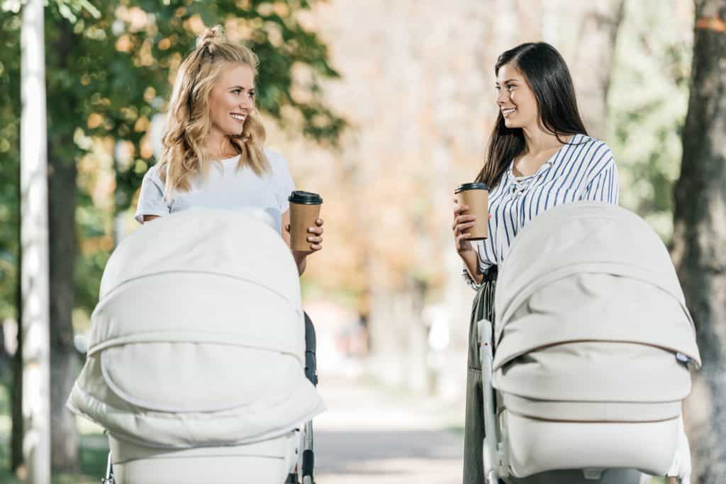 women walking in park with strollers drinking coffee